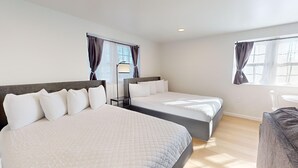 Ein Hotelzimmer mit zwei Betten, einem Schreibtisch und einem Sessel.