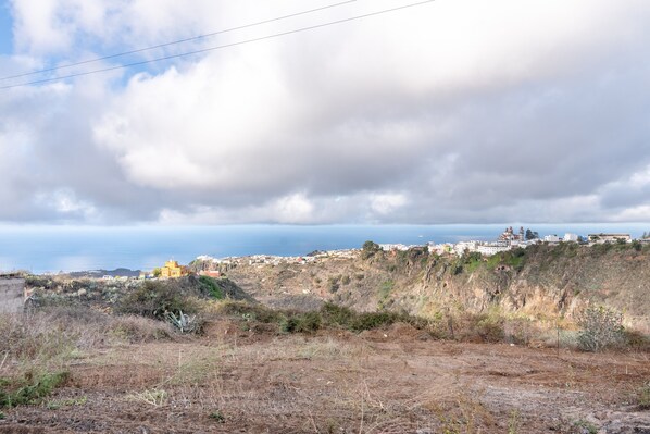 A coastal landscape with a view of a town and a hill with buildings.