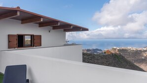 A white building with a balcony overlooking a coastal view.