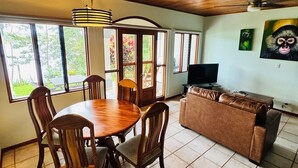 Ein Essbereich mit Holztisch und Stühlen, einer Couch und einem Fernseher.