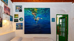 Ein Zimmer mit einem Bett, einer grünen Tür und einem großen Gemälde von einer Person, die unter Wasser schwimmt.