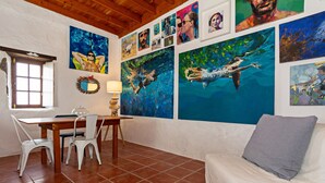 Ein Zimmer mit Esstisch, Stühlen, einer Couch und Bildern an den Wänden.