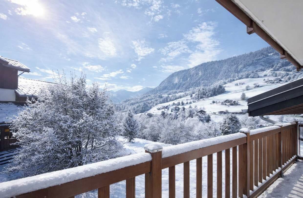 A snow-covered mountain landscape with a wooden balcony railing.