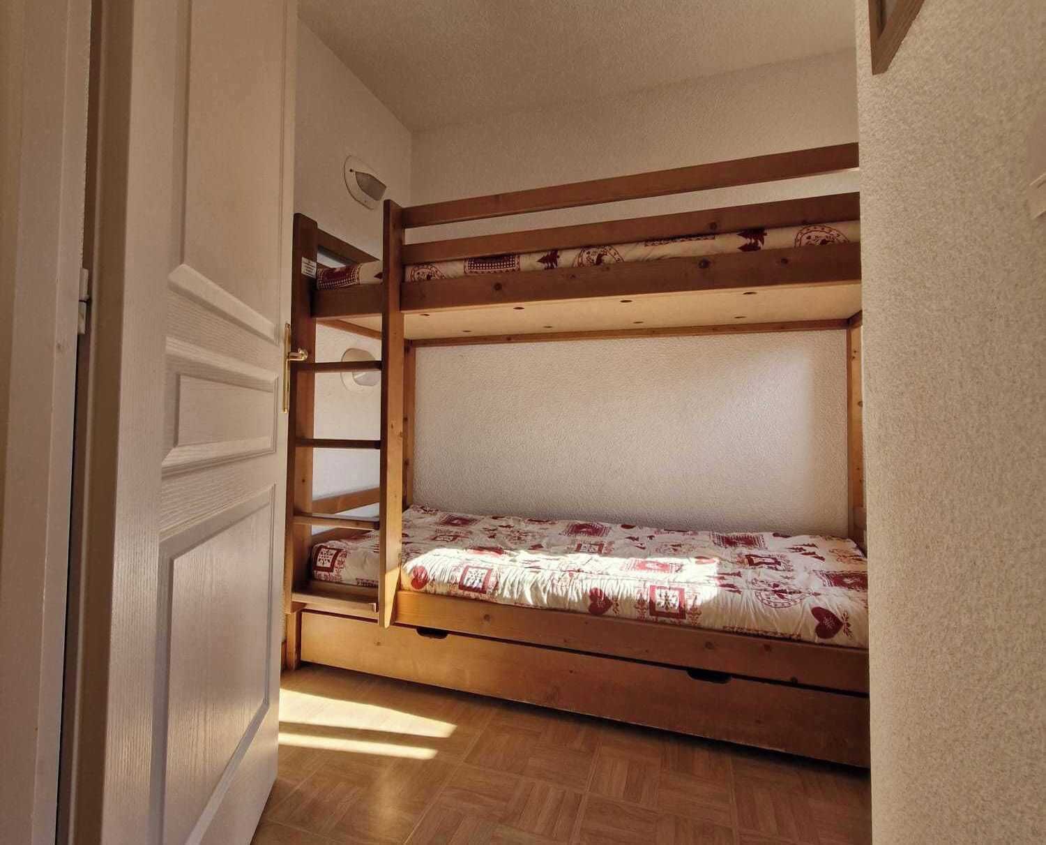 A bunk bed with a wooden frame and a patterned mattress.