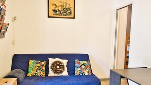 A blue sofa with colorful pillows, a framed picture on the wall, and a wooden table.
