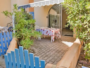 A patio area with a table set for dining, surrounded by a blue fence and greenery. - T3 with parking and terrace next to the sea (Leucate)