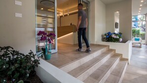 A modern hotel entrance with a person walking up the steps.