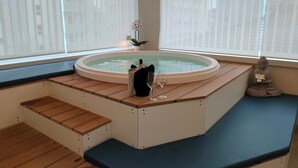 A hot tub with wooden steps and a bench, surrounded by large windows with sheer curtains.