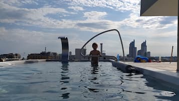 Una piscina al aire libre, sombrillas, sillones reclinables de piscina