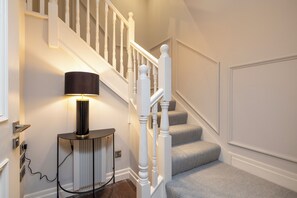 Staircase leads to an upper floor, accompanied by a table lamp and door.