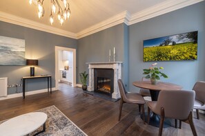 Cozy living space with a fireplace, dining area, and large landscape painting.
