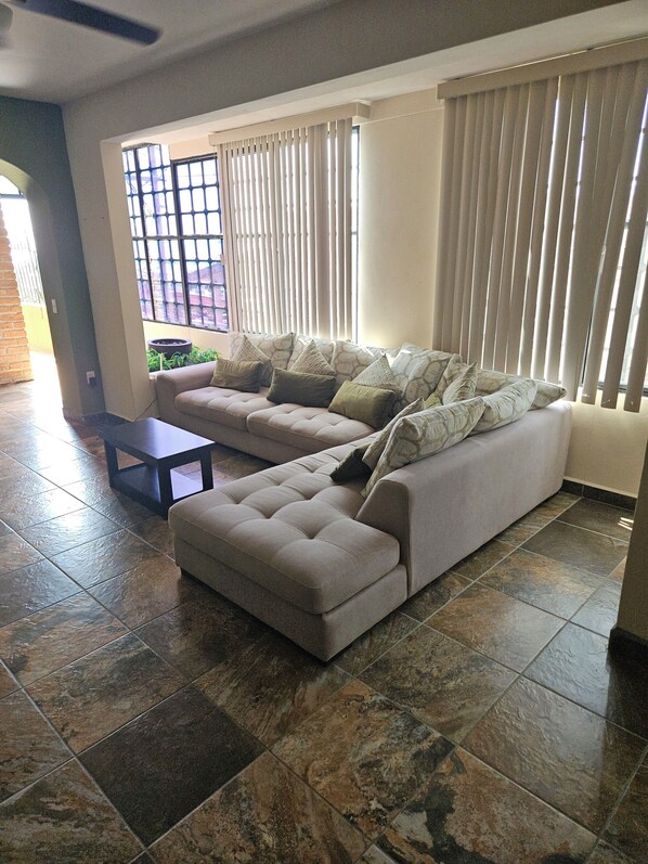 Una sala de estar con un sofá, una mesa de centro y una ventana con persianas.