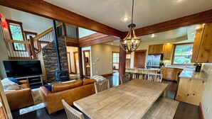 A spacious living area with a large wooden dining table, leather sofas, and a stone fireplace. - Luxurious Home in Magical McCall (McCall)