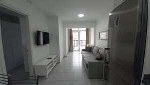 A modern living room with a flat-screen TV, a sofa, a coffee table, and a refrigerator. - Vacation Home 'Las Palmeras 522 Puerto Feliz' with Sea View, Wi-Fi and Air Conditioning (Puerto Rico)