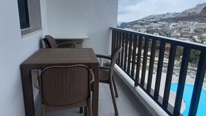 A balcony with a table and chairs, a view of a cityscape, and a swimming pool. - Vacation Home 'Las Palmeras 522 Puerto Feliz' with Sea View, Wi-Fi and Air Conditioning (Puerto Rico)