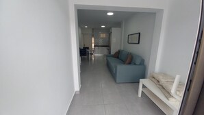 A modern living room with a sofa, a bench, and a kitchen in the background. - Vacation Home 'Apartamento Sol 523 Puerto Feliz' with Sea View, Wi-Fi and Air Conditioning (Puerto Rico)