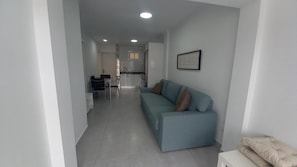 A modern living room with a sofa, a dining area with chairs, and a kitchen in the background. - Vacation Home 'Apartamento Sol 523 Puerto Feliz' with Sea View, Wi-Fi and Air Conditioning (Puerto Rico)