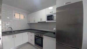 A modern kitchen with white cabinets, a stainless steel refrigerator, a microwave, and a built-in oven. - Vacation Home 'Apartamento Sol 523 Puerto Feliz' with Sea View, Wi-Fi and Air Conditioning (Puerto Rico)
