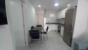 A modern kitchen with white cabinets, a stainless steel refrigerator, and a dining area with a glass table and chairs. - Vacation Home 'Apartamento Sol 523 Puerto Feliz' with Sea View, Wi-Fi and Air Conditioning (Puerto Rico)