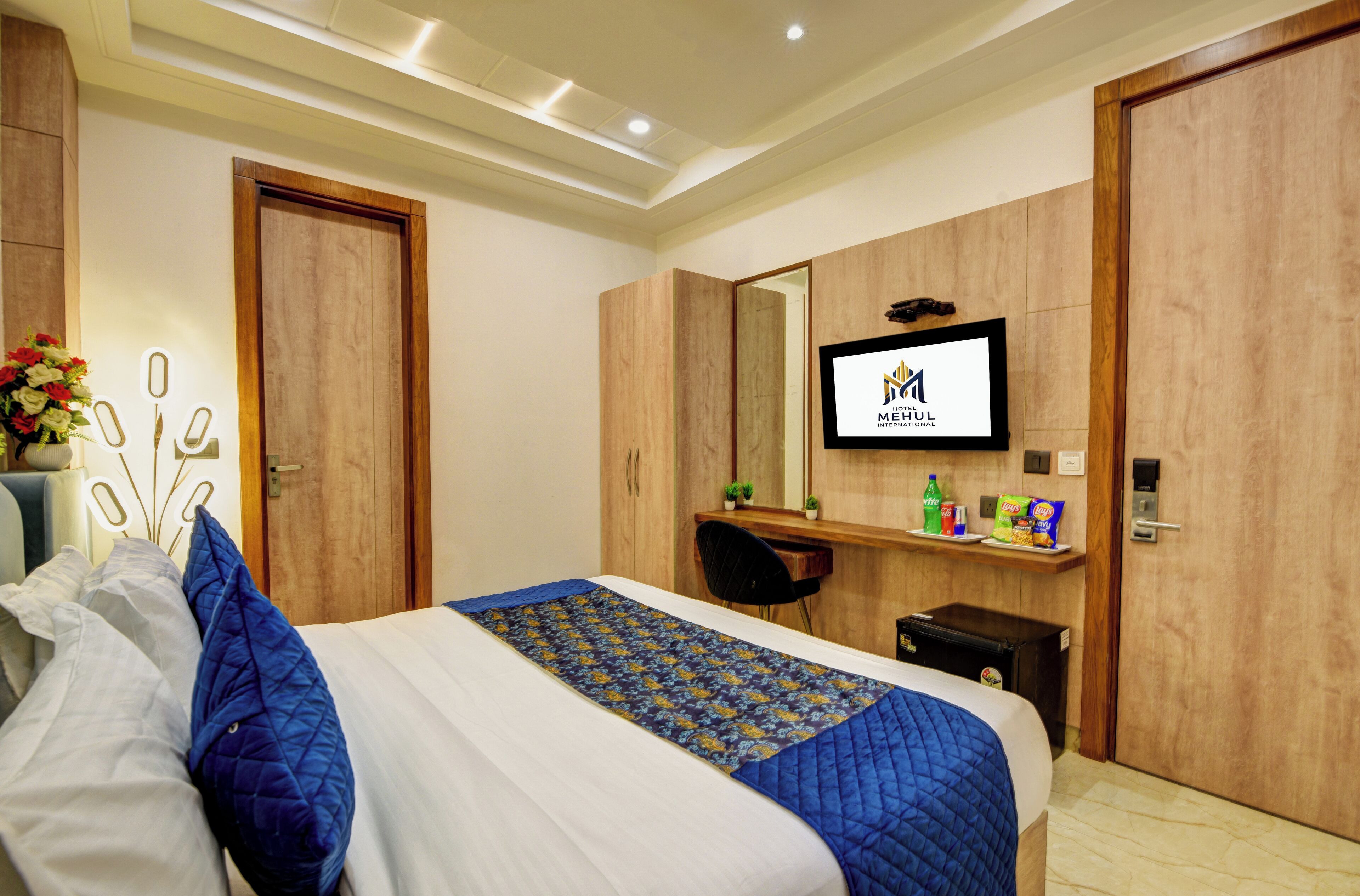 A hotel room with a bed, a desk, a mirror, and a television.