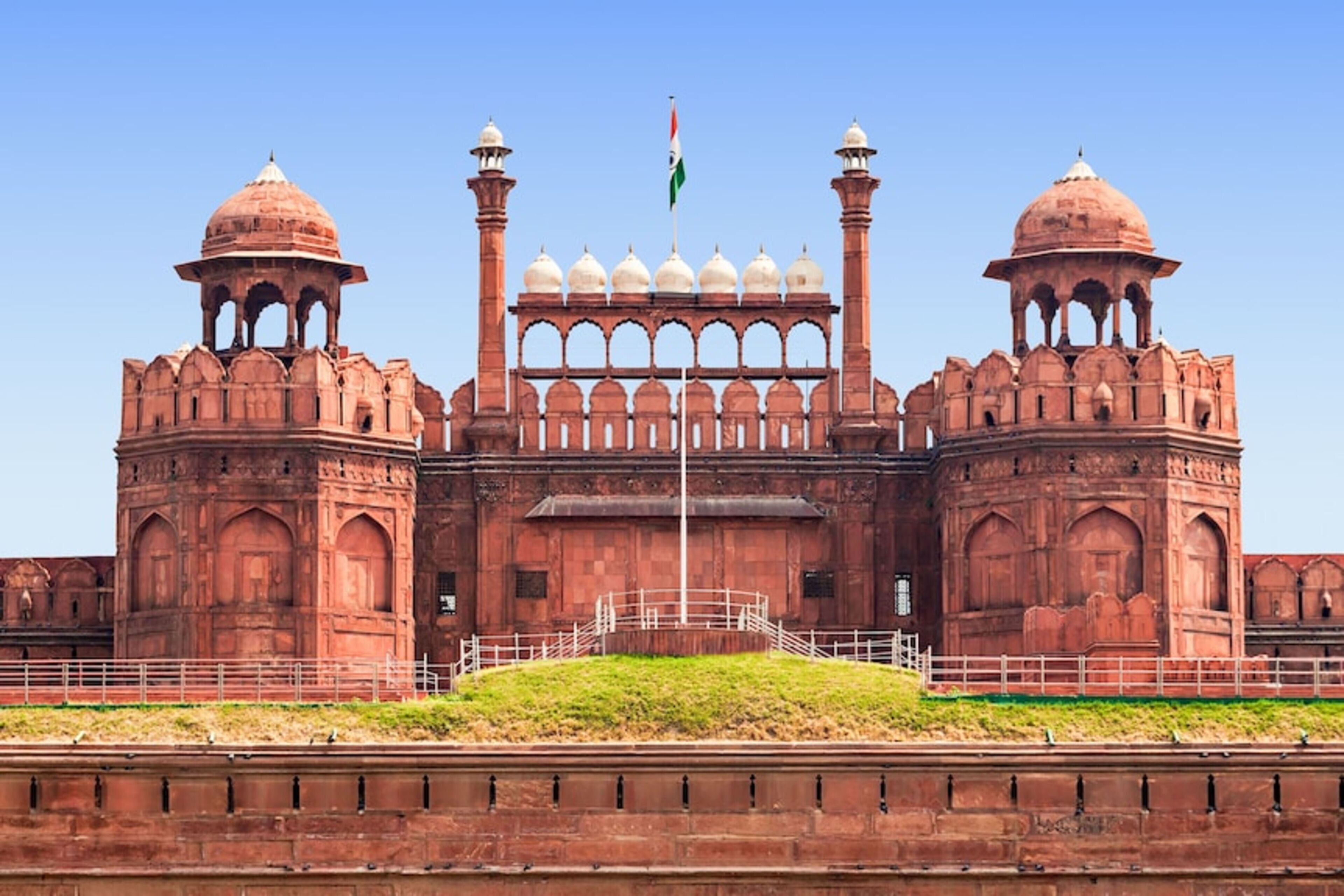 A large, historic building with two prominent domes, a central archway, and a flagpole with a flag.