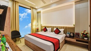 Une chambre d’hôtel moderne dotée d’un grand lit, d’un bureau avec une chaise, d’un ventilateur de plafond et offrant une vue sur le ciel par une fenêtre.