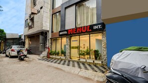 Un hôtel appelé « Hotel Mehul Int. », doté d’une façade moderne, de grandes fenêtres et d’une entrée accueillante.