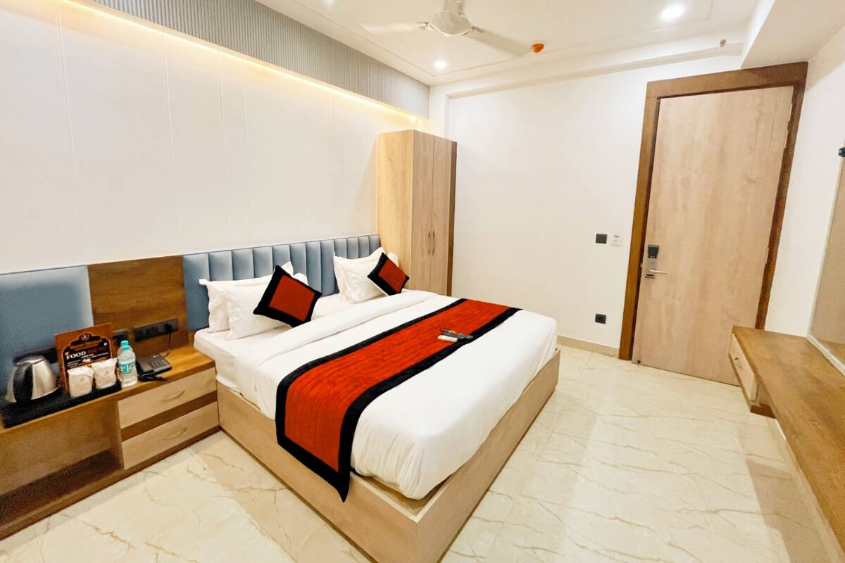 Una habitación de hotel moderna con una cama grande, mesitas de noche, un armario y un ventilador de techo.