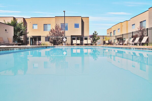 A swimming pool with lounge chairs and a building with multiple windows and doors. - Entrada at Moab 624 (Moab)