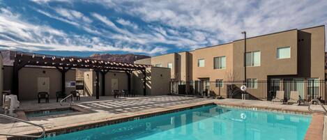 A swimming pool with a pergola, outdoor chairs, and a view of mountains.