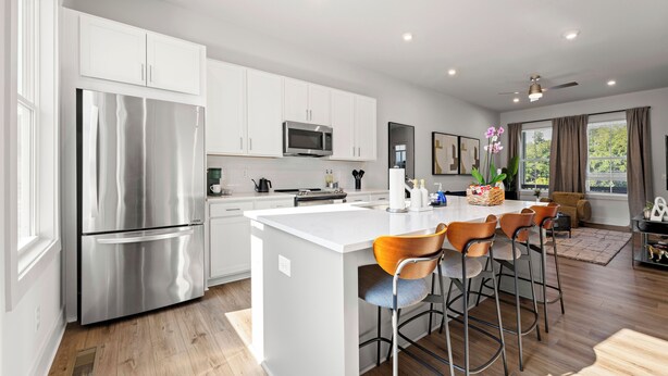 A modern kitchen with white cabinets, stainless steel appliances, and a central island with bar stools.