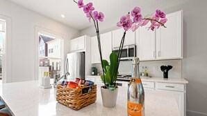 A kitchen with white cabinets, a stainless steel refrigerator, a microwave, and a potted plant.