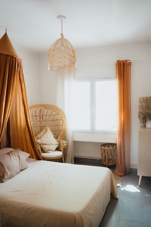 A bedroom with a bed, a wicker chair, a window, and a hanging light fixture. - Holiday Home 'Domaine Montserrat' with Mountain View, Private Pool and Wi-Fi (Le Luc)