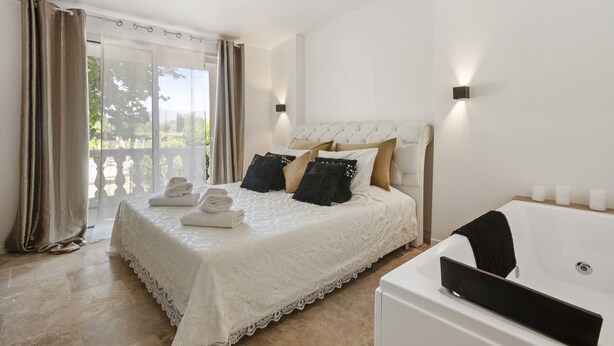 Un dormitorio con una cama grande, un cabecero blanco y una bañera.