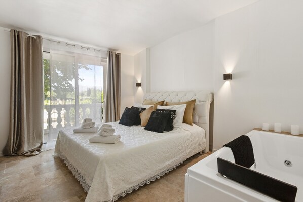 Une chambre à coucher avec un grand lit, une tête de lit blanche et une baignoire.