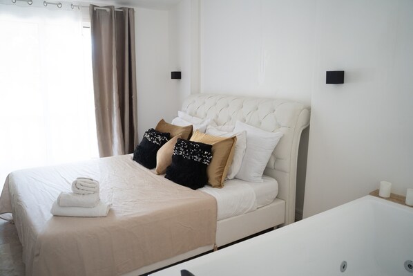 A hotel room with a bed, a bedside table, and a bathroom with a bathtub. - Holiday Home 'Domaine Montserrat' with Mountain View, Private Pool and Wi-Fi (Le Luc)