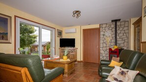 A living room with a sofa, a coffee table, a television, and a stone wall.