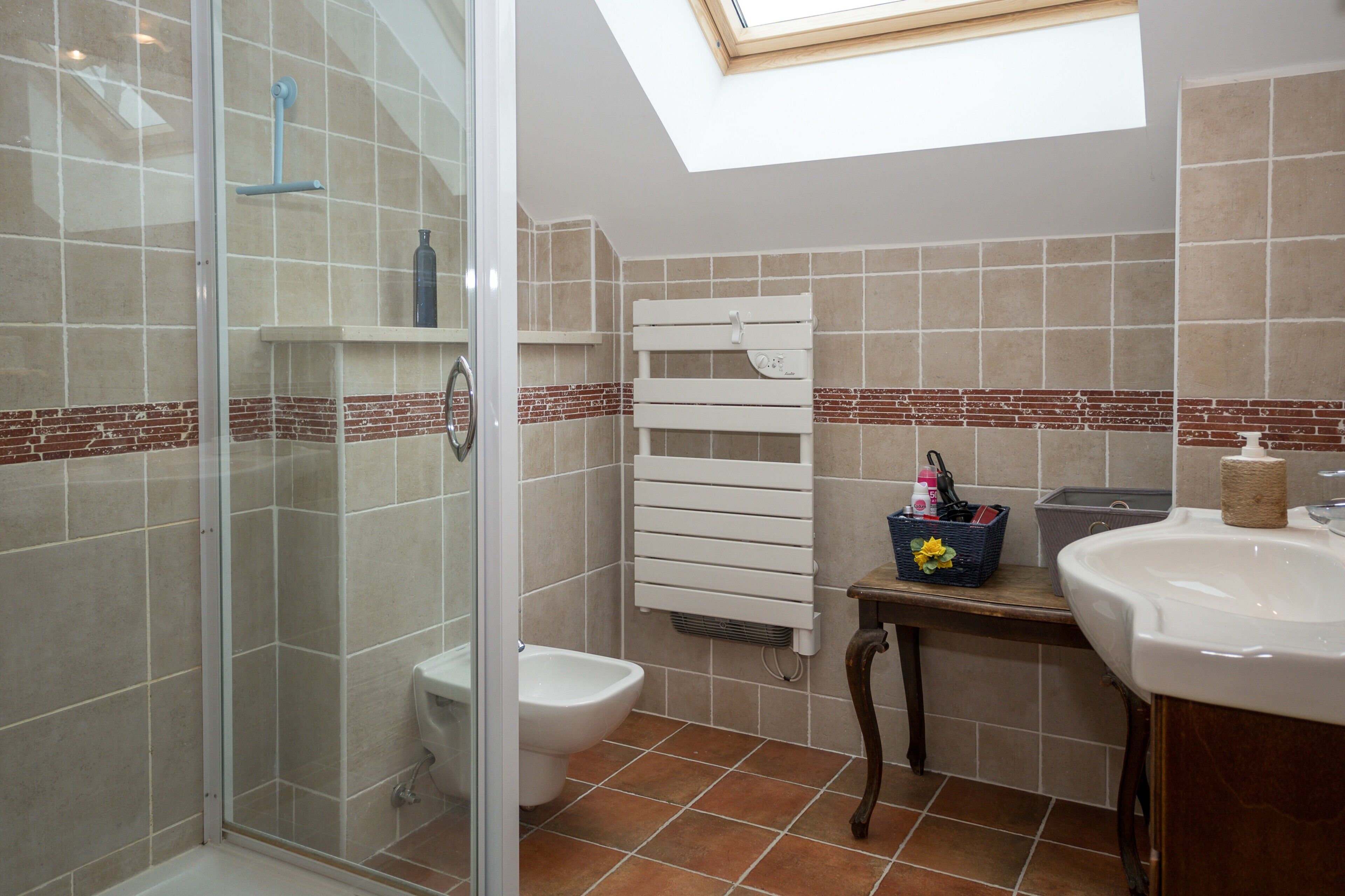 Une salle de bain équipée d’une douche, de toilettes et d’un lavabo, ainsi que d’un porte-serviettes et d’une lucarne.