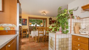 A kitchen with wooden cabinets, a tiled backsplash, a dining table with chairs, and a potted plant.