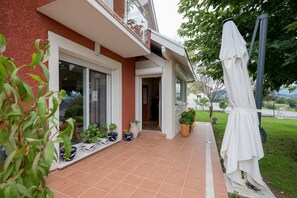 Een huis met een rode gevel, een balkon en bloempotten op het terras.