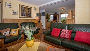 A living room with two sofas, a coffee table, and a vase with plants. There are framed pictures on the wall.
