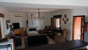 Ein Wohnzimmer mit Fernseher, Kamin, einer Deckenleuchte und einer mit Vorhängen versehenen Tür.