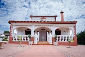 A two-story building with a central entrance, arched doorways, and a balcony with railings.
