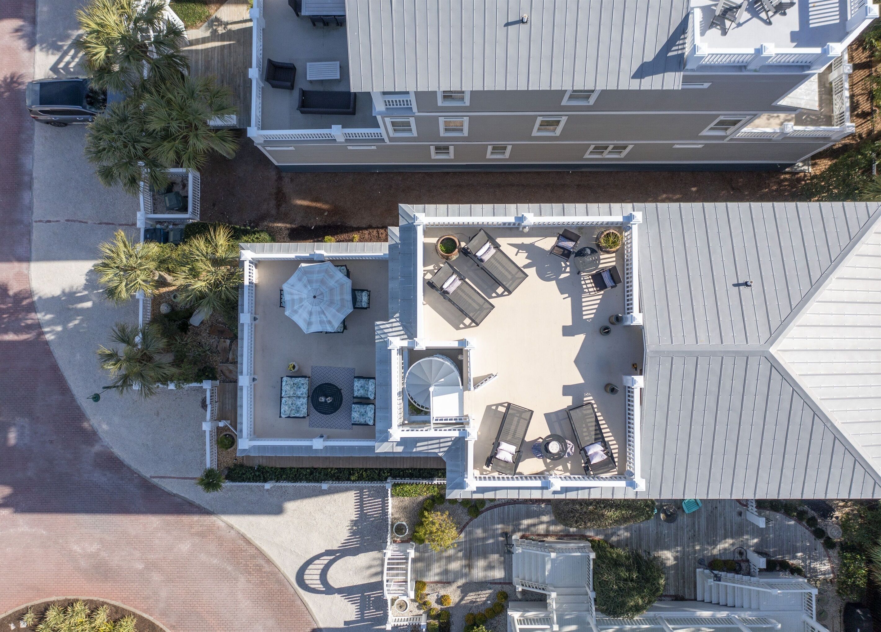 An aerial view of a rooftop patio with outdoor seating, a large umbrella, and a pool table.