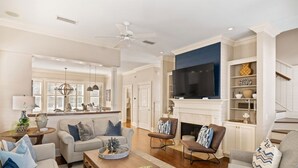 A spacious living room with a fireplace, a television, and a staircase.