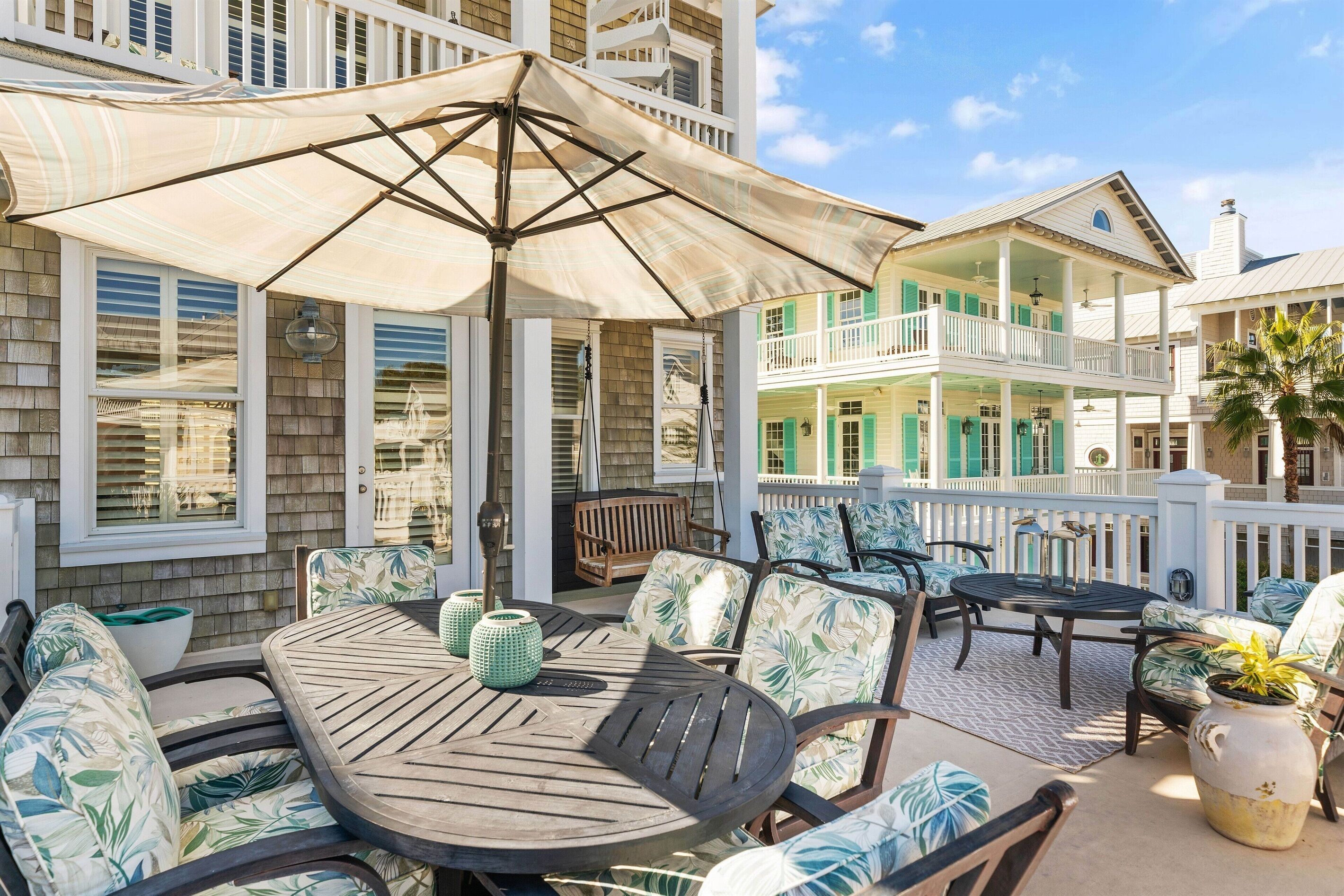 Un espace extérieur aménagé avec une zone de repos couverte, comprenant une table et des chaises, un grand parasol et une vue sur un immeuble à plusieurs étages doté de balcons.