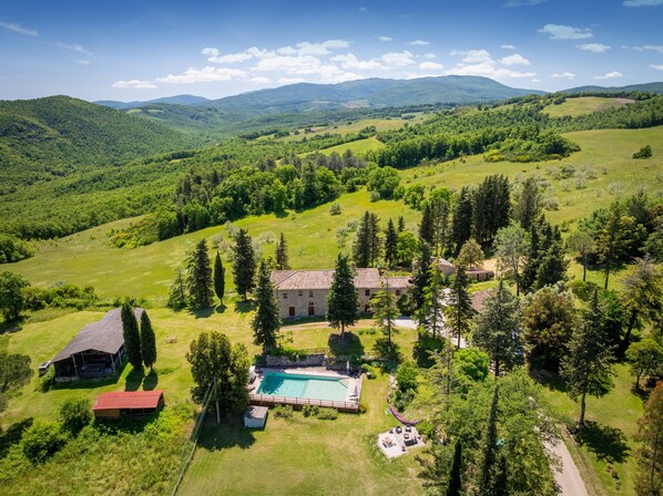 A rural property with a swimming pool, a large house, and surrounding greenery.