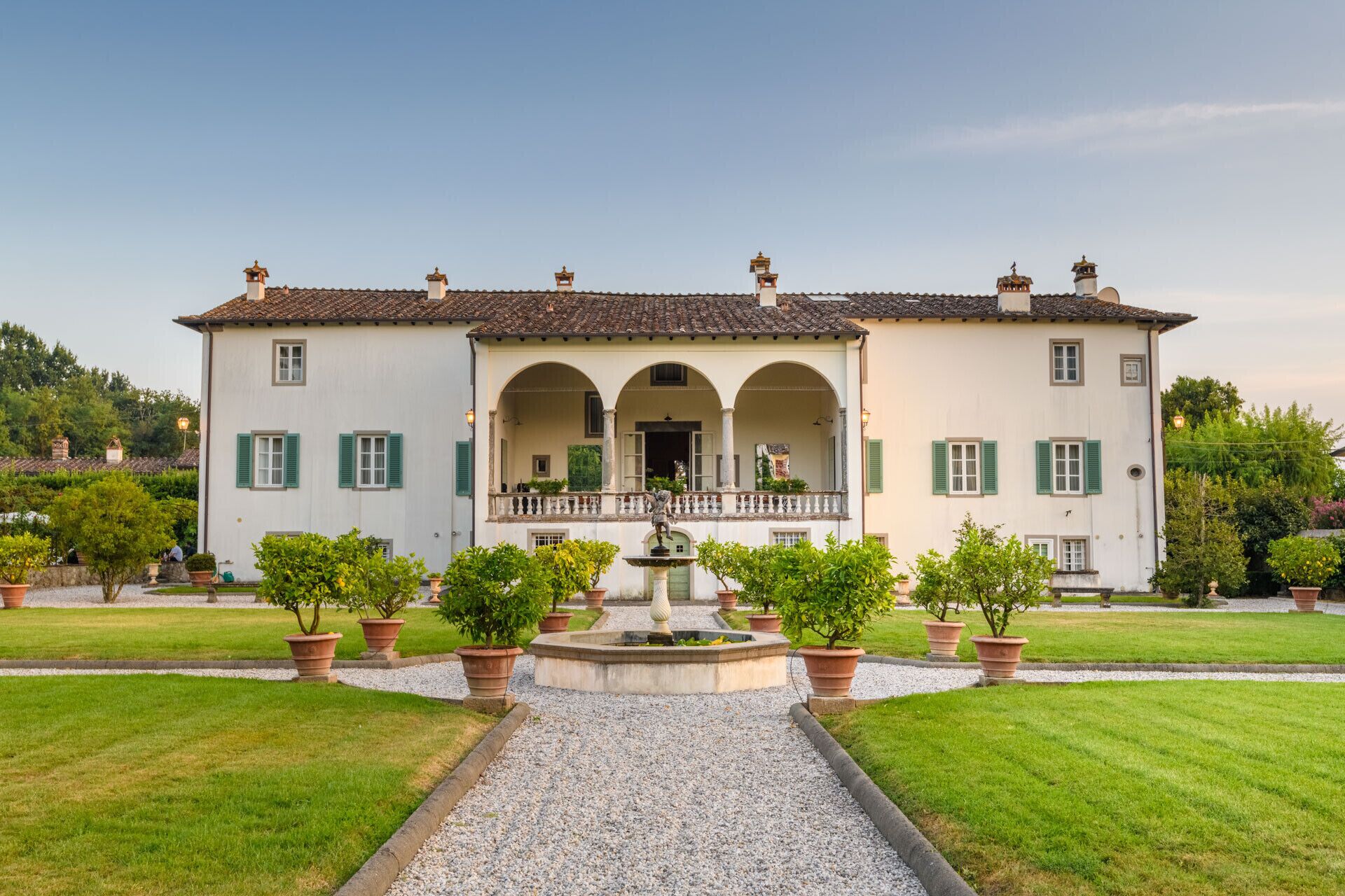 A large, two-story building with a central courtyard, featuring a fountain and potted plants.