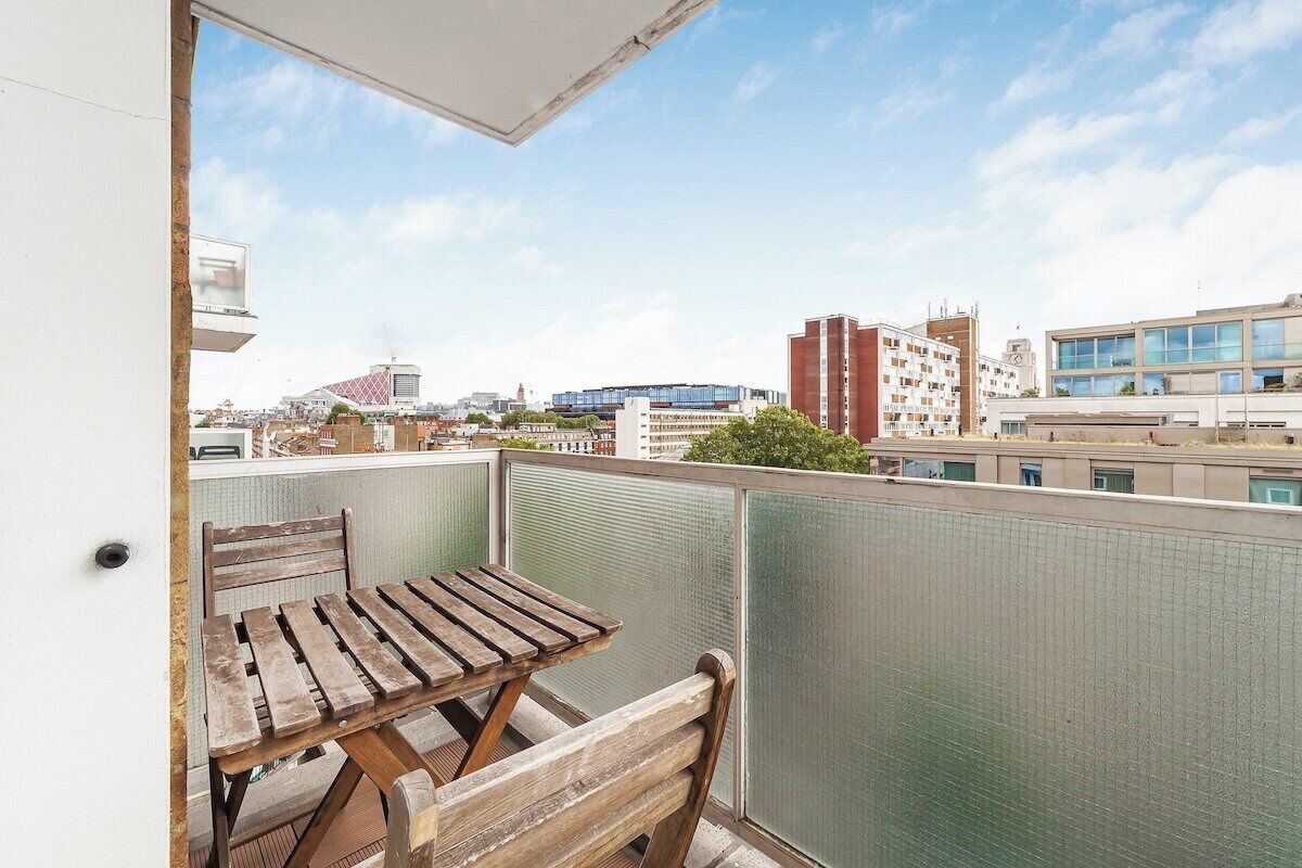 Un balcón con mesa y silla de madera, que ofrece vistas de la ciudad.