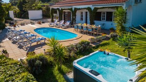 A pool area with lounge chairs, a hot tub, and a dining table set outdoors.
